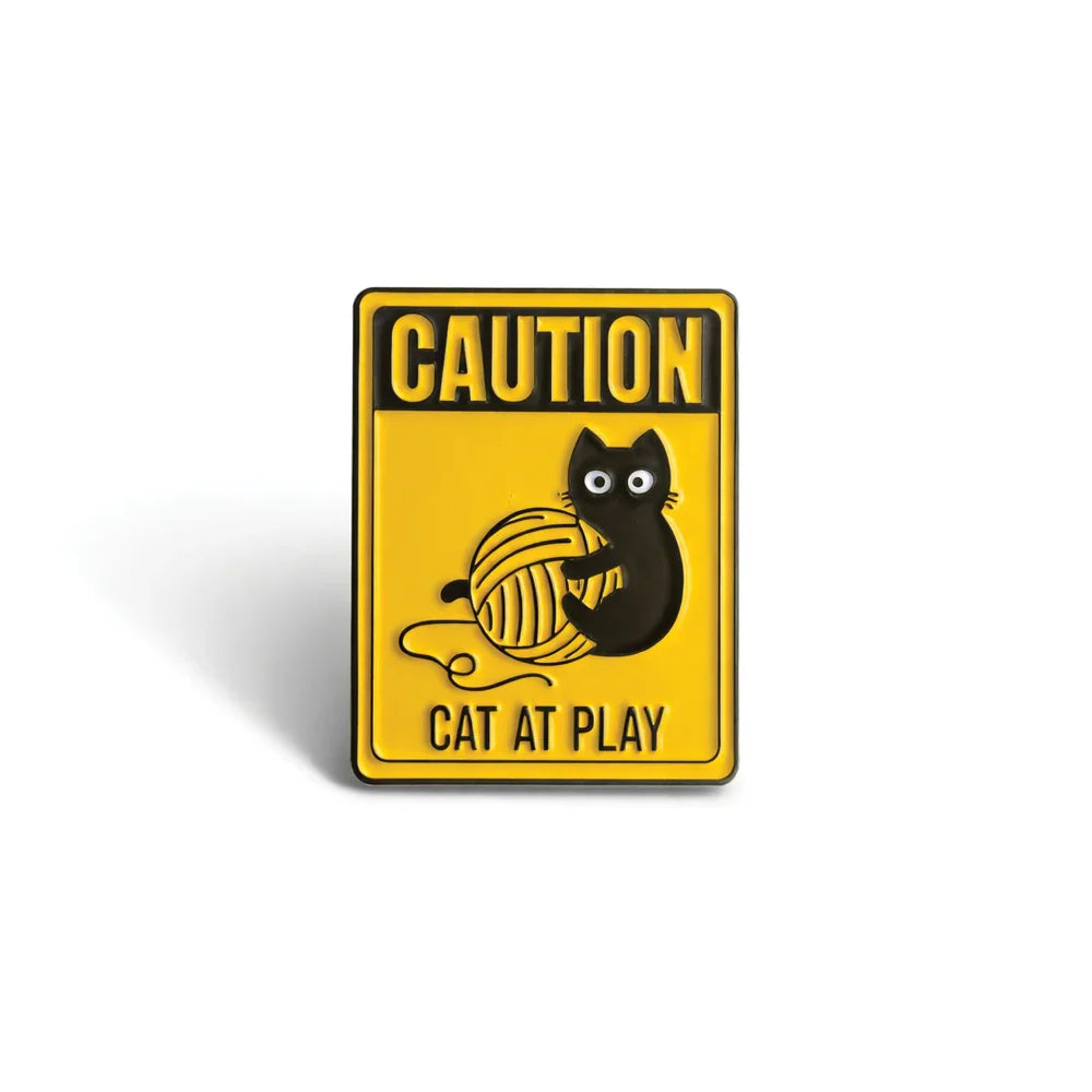 Yellow caution sign pin with black cat playing with yarn ball, Soulpurrpose themed accessory.