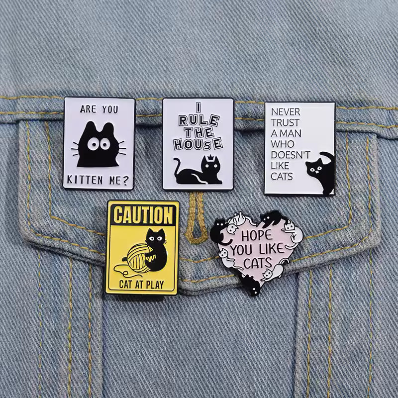 Cute black cat-themed enamel pins with funny quotes on a denim jacket pocket, Soulpurrpose style