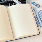 Open blank notebook on laptop with blue pen and cute animal-themed stationery, Soulpurrpose